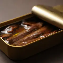Latas doradas abiertas con las mejores anchoas del mundo, sumergidas en aceite.