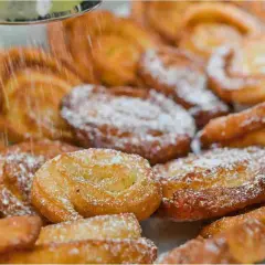 Dolci fritti cosparsi di zucchero a velo, perfetti per il Carnevale. Sembrano deliziosi limoncini, pronti per essere gustati.