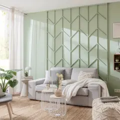 Eine stilvolle Wand hinter der Couch gestalten mit einem geometrischen Paneel in Mintgrün. Gemütliche Atmosphäre mit hellgrauem Sofa, Kissen und Decke.