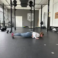 Frau macht Liegestütze im Fitnessstudio, ein Teil ihres plyometrischen Trainings.