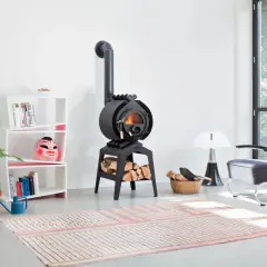 Ein gemütliches Wohnzimmer mit einem Bullerjan B3 Keramik Ofen, der Holzscheite wärmt. Daneben ein Bücherregal mit einer bunten Maske.