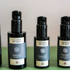 Cinco envases de productos de belleza "Secretos del Agua": agua de musgo, mousse facial, peeling selectivo, crema antiaging y contorno de ojos.