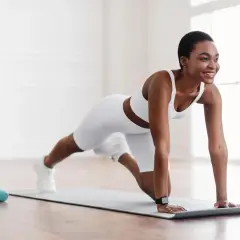 Frau in weißer Sportkleidung macht Liegestütze auf einer Matte. Tolle Fitness-Tipps für ein starkes Körpergefühl.