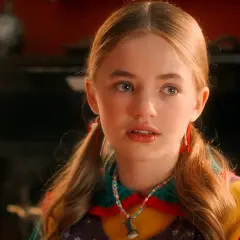 Holly Wheeler aus Stranger Things mit Zöpfen und einer bunten Halskette.