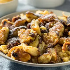 Ein Teller mit köstlichem, zerkleinertem Kaiserschmarrn, bestäubt mit Puderzucker und Rosinen. Eine leckere low carb Variante!
