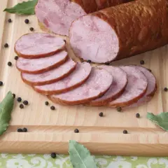 Kiełbasa szynkowa wędzona, pokrojona w plastry, na desce z pieprzem i liśćmi laurowymi. Idealna do domowego przepisu.