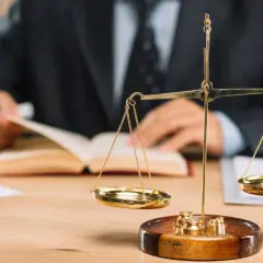 Prawnik analizuje dokumenty, przygotowując się do sprawy o odszkodowanie za bezumowne korzystanie. Waga sprawiedliwości symbolizuje równowagę.