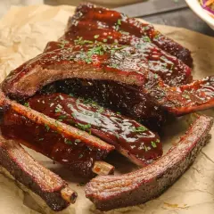 Délicieuses ribs partie du porc, nappées de sauce barbecue et parsemées de persil frais. Un délice à savourer !