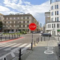 Widoczny znak stop na skrzyżowaniu ulic. Po prawej stronie budynek z napisem "Żabka".