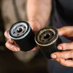 Dwa filtry oleju w dłoniach mechanika. Jeden nowy, drugi stary i brudny, dowód na to, że za mocno dokręcony filtr oleju może sprawić problemy.
