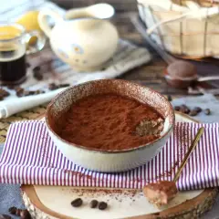 Schüssel mit Tiramisu Overnight Oats, bestäubt mit Kakao. Ein Löffel mit dem Dessert liegt daneben.