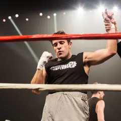 A boxer's arm is raised in victory, a moment of triumph in amateur vs professional boxing. The crowd roars as the referee declares the winner.