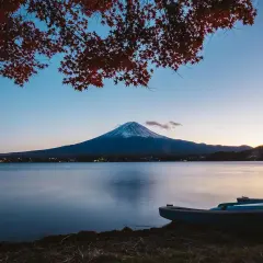 Zachód słońca nad jeziorem z łodziami i górą Fudżi w tle. Zastanawiasz się, ile się leci do Japonii, patrząc na ten widok?