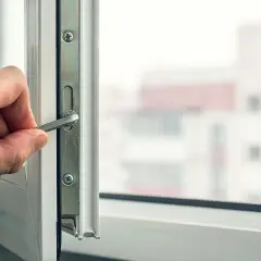 Dłoń dokręca śrubę w ramie okna, przygotowując do wymiany pakietu szybowego.