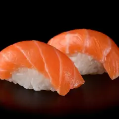 Dwa kawałki sushi z łososiem, idealna ryba do sushi, na czarnym tle.