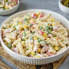Herzhafte Nudelsalate mit Mayonnaise, gefüllt mit Erbsen, Mais und Schinkenwürfeln. Perfekt für ein schnelles Mittagessen.