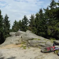 Odpoczynek na skalnej półce po trudnej trasie rowerowej. W tle las i błękitne niebo.