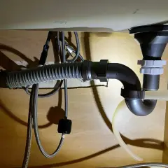 Pod zlewem widać instalację hydrauliczną z syfonem i elastycznym wężem odpływowym. Widać też trójnik, który rozdziela odpływ.