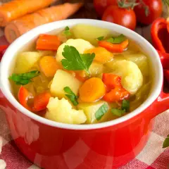 Aromatyczna zupa jarzynowa kcal, pełna warzyw: marchewki, ziemniaków, kalafiora i papryki, ozdobiona natką pietruszki.