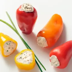 Des mini poivrons farcis colorés, garniture crémeuse et herbes fraîches, prêts à être dégustés.