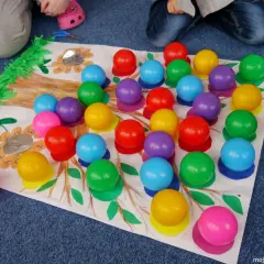 Kolorowe kulki na tle rysunku drzewa i kwiatów.