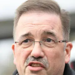 Nahaufnahme von Manfred Wagner mit Brille und Schnurrbart, der nachdenklich in die Kamera blickt.