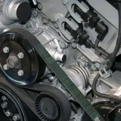 Detalle del motor de un coche, mostrando la polea y la correa de distribución.