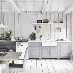 Ljust och luftigt kök med vit inredning inspiration. Träpaneler på väggar och tak, gråa skåp och ett vitt porslinsho. Ett kök som andas lugn och harmoni.
