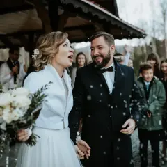Szczęśliwa para młoda, w otoczeniu gości, świętuje swoje wesele w adwencie. Sypią się płatki, tworząc magiczną atmosferę.