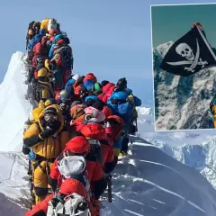 Kolejka wspinaczy na szczycie Everestu. W rogu pirat z flagą, wszystko za Everest.