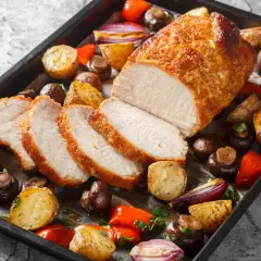 Schab pieczony w piekarniku, soczysty i rumiany, podany z pieczonymi ziemniakami, pieczarkami, papryką i czerwoną cebulą.