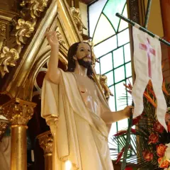 Figura Jezusa z chorągwią z krzyżem, otoczona złotymi zdobieniami i kwiatami. Symbolizuje zwycięstwo i nadzieję, przypominając o tym, ile trwaja rezurekcje.