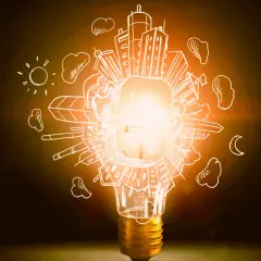 Bombilla encendida con dibujos de ciudad, sol y luna. Representa la diferencia entre potencia y energía, la chispa de una idea.