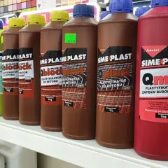 Rzędy butelek z dodatkami do cementu: plastifikatory do betonu i zapraw budowlanych. Różne kolory i pojemności.