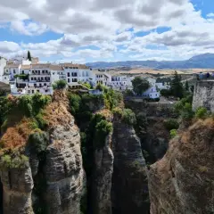 El mirador La Hoya del Tajo ofrece vistas espectaculares de casas blancas al borde de un profundo tajo, con gente admirando el paisaje.