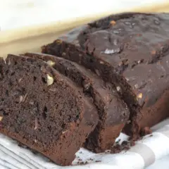 Bizcocho de platano y chocolate, recién horneado y cortado en rebanadas, con trozos de nuez visibles.