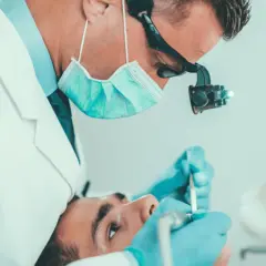 Dentysta wykonuje leczenie kanałowe jedynki, używając mikroskopu i specjalistycznych narzędzi.