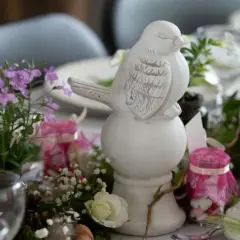 Décoration de table printanière avec un oiseau en céramique, fleurs et bougies roses. Idéal pour une célébration comme un baptême civil, une démarche simple et élégante.
