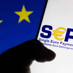 Logo SEPA na ekranie telefonu, na tle flagi UE. Czy w Albanii można płacić euro? SEPA to obszar jednolitej płatności w euro.