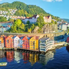 Kolorowe kamienice nad wodą, wzgórza z domkami w tle – to malownicza Norwegia latem.