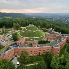 Widok z lotu ptaka na Kopiec Kościuszki z krętymi ścieżkami. Widać ceglaną fortecę i otaczający ją las.