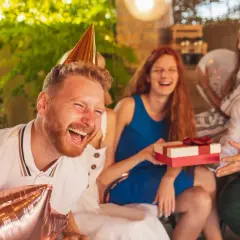 Impreza urodzinowa koleżanki w pełni! Wszyscy się śmieją, a on ma na głowie stożek i trzyma balony.