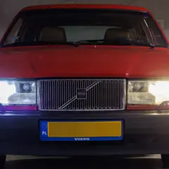 Czerwone Volvo z włączonymi światłami. Czy ledy mogą się zapalić? Tak, te świecą jasno, oświetlając parking.
