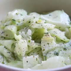 Cremiger Gurkensalat, ein einfaches und erfrischendes gurkensalat rezept, garniert mit Kräutern und Pfeffer.