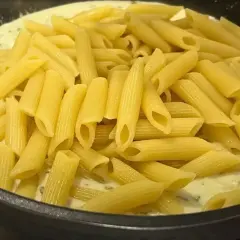 Smażony makaron penne w kremowym sosie z ziołami, gotowy do podania.