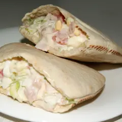 Dos deliciosos bocadillos de pan pita rellenos de ensalada cremosa, jamón y huevo.