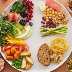 Un piatto colorato con salmone, verdure, frutta, legumi e cereali, un esempio di dieta per disbiosi intestinale.