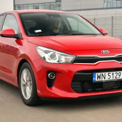 Czerwony Kia Rio 4 w ruchu, z kierowcą za kierownicą.