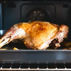 Un gigot d'agneau doré et juteux cuit dans un plat au four, prêt à être dégusté.
