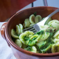 Orecchiette con cime di rapa, uno dei piatti tipici foggiani, servite in una ciotola di terracotta con una forchetta.